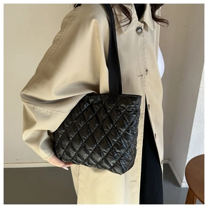 Detailed view of black quilted nylon tote bag featuring wide webbed carry handles