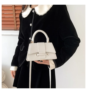 Detailed view of white pleated PU leather handbag featuring a round eyelet and top handle