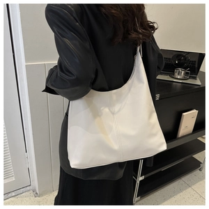 Detail of a large cream PU leather tote bag showing soft texture and vertical stitching