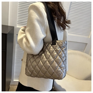 Close-up of metallic quilted tote bag with black straps on a white cashmere coat