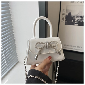 Détail d'un mini sac à main blanc orné d'un nœud en strass et d'une bandoulière en chaîne