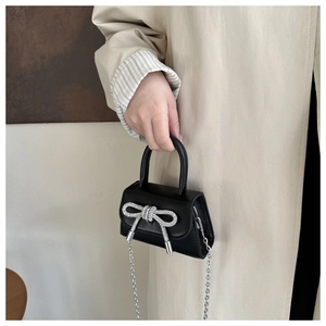 Détail d'un mini sac à bandoulière noir avec un nœud étincelant en strass argentés