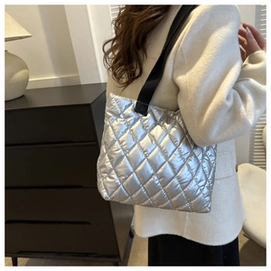 Macro shot of silver quilted puffer tote bag fabric with metallic finish and black strap