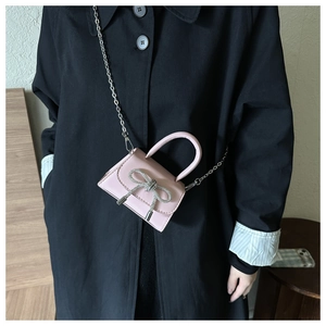 Détail du mini sac carré rose avec un nœud en strass brillant et une chaîne argentée