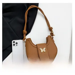 Close-up of brown pebbled leather half-moon bag featuring a gold butterfly buckle closure