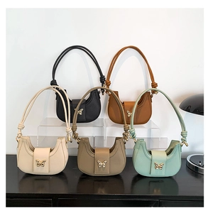 Detailed view of half-moon underarm bags with gold butterfly buckles and knotted straps