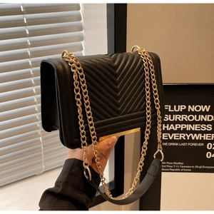 Detailed view of black quilted leather crossbody bag with golden chain and metal buckle