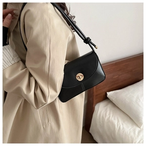 Close-up of a black vintage crossbody bag with a gold twist lock and a leather knot strap
