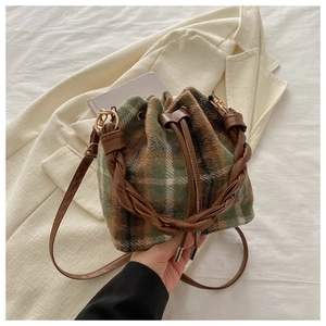 Close-up of vintage plaid drawstring bucket bag with leather trim on neutral background