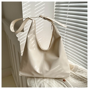 Detail of minimalist cream shoulder bag with broad strap and elegant shutter shadows