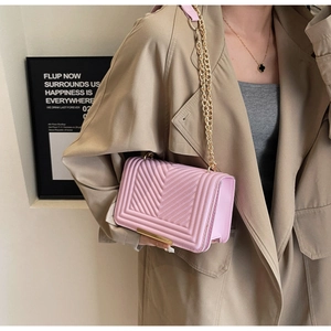 Close-up of pink quilted chain bag worn with a stylish trench coat in soft light