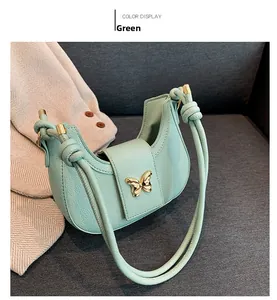 Detail of mint green crescent bag featuring a gold butterfly buckle and knotted strap