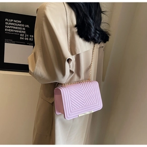 Detail of pink V-quilt crossbody bag featuring gold chain strap and metal trim hardware