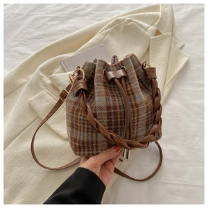 Close-up of brown and blue plaid bucket bag with woven handle and drawstring detail