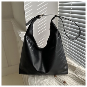 Detail of a black leather tote bag with vertical stitching on a knit background