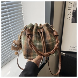 Close-up of retro plaid drawstring bucket bag with fuzzy charm and woven handle