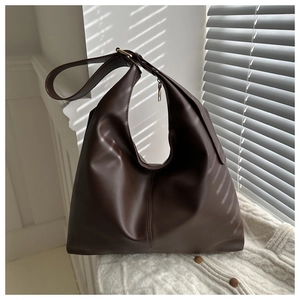 Detailed view of dark brown Hobo bag on white knitwear with natural sunlight and shadows
