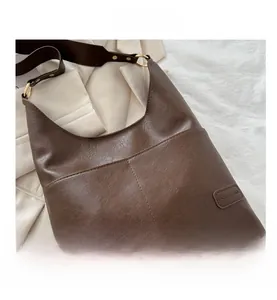 Dettaglio ravvicinato della borsa hobo marrone scuro con trama in pelle e anelli in metallo