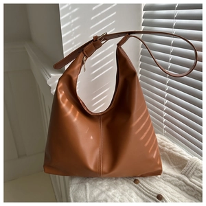 Detailed view of brown matte leather tote bag with vertical stitching and metal buckle strap