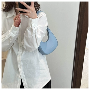 Mirror selfie showing the light blue crescent shoulder bag for fit and size perspective
