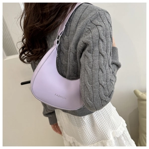 Woman wearing a light purple crescent shoulder bag with silver Fashion logo detail