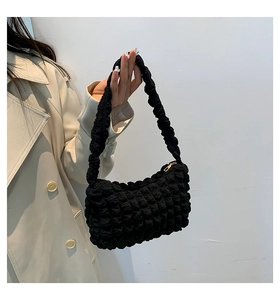Gros plan détaillé d'un sac à bandoulière noir à texture popcorn et fermeture éclair dorée