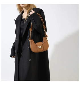 Close-up of brown litchi pattern leather underarm bag with golden butterfly buckle
