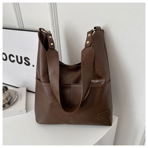 Dettaglio borsa Hobo marrone scuro con tasca anteriore e rivetti dorati sulla tracolla