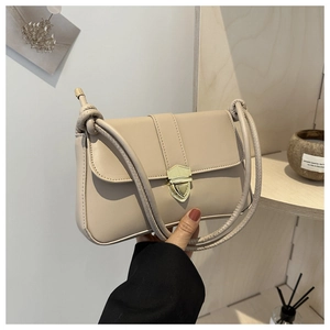 Nahaufnahme der beigen Lederhandtasche mit goldener Schildschnalle und Knotenschultergurt
