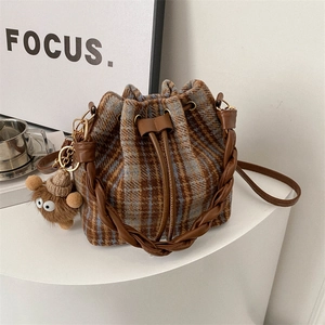 Brown and blue plaid drawstring bucket bag with woven handle and plush charm accessory