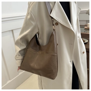 Dettaglio di una borsa tote in ecopelle marrone indossata con un trench bianco