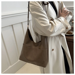 Borsa hobo marrone in ecopelle con cuciture fini e ampia tracolla indossata da modella