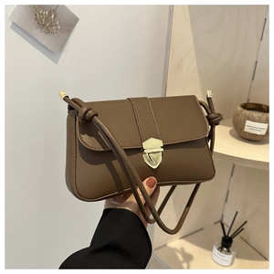 Detailansicht der braunen PU-Leder Umhängetasche mit goldenem Schildschloss in der Hand