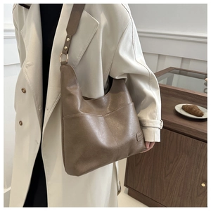 Dettaglio di una borsa hobo marrone con ampi spallacci con borchie e anello in metallo vintage