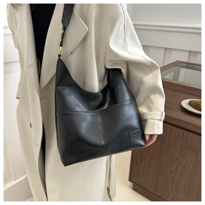 Dettaglio della borsa hobo vintage in pelle nera con fibbie dorate e tracolla larga