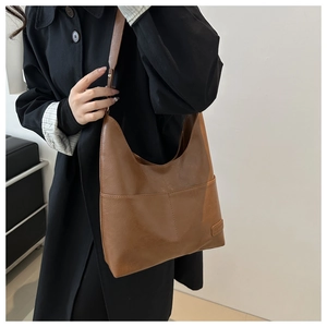 Dettaglio della grande tasca frontale e texture della pelle su una borsa marrone