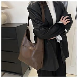 Dettaglio di borsa tote marrone scuro con cuciture decorative ed etichetta moda