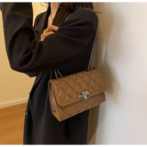 Dettaglio della borsa in pelle trapuntata marrone con catena e chiusura in metallo