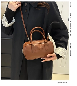 Detail of brown faux leather handbag showing the embossed FASHION logo and texture