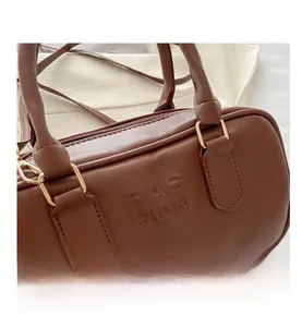 Detail view of caramel faux leather Boston bag with gold hardware and fashion embossing