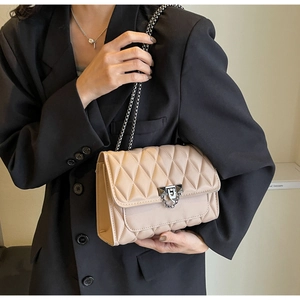 Dettaglio borsa trapuntata beige con chiusura metallica argento e tracolla a catena