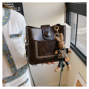 Detail of dark brown bucket bag with lychee texture and cute rabbit charm pendant