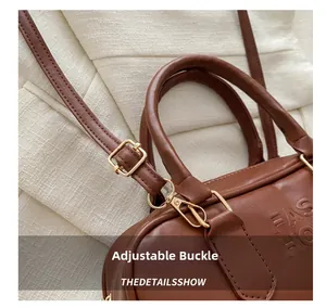 Detail view of the brown leather handbag with adjustable gold buckle and strap