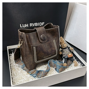 Detail of dark brown bucket bag featuring ethnic wide strap and cute rabbit charm