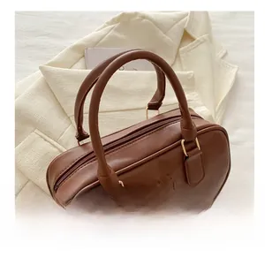 Detail of brown cylinder leather handbag featuring embossed FASHION lettering on the front