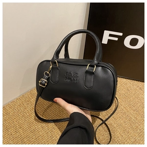 Detailed shot of black faux leather handbag featuring embossed lettering and gold hardware