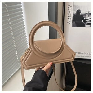 Close-up of khaki geometric trapezoid handbag with distinctive round handle and PU leather