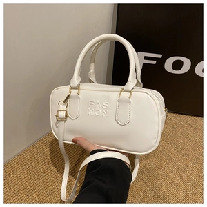 Detailed macro view of embossed FAS HON letters on cream white leather handbag texture