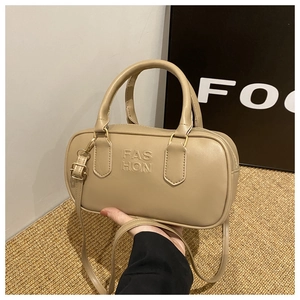 Detailed shot of beige leather Boston bag featuring embossed FASHION logo and gold hardware