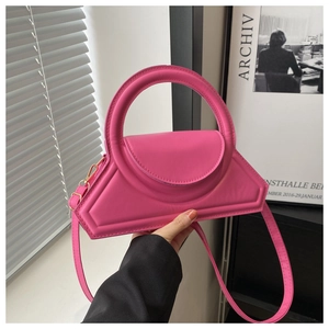 Macro shot of rose pink leather handbag with round handle and gold metal hardware detail